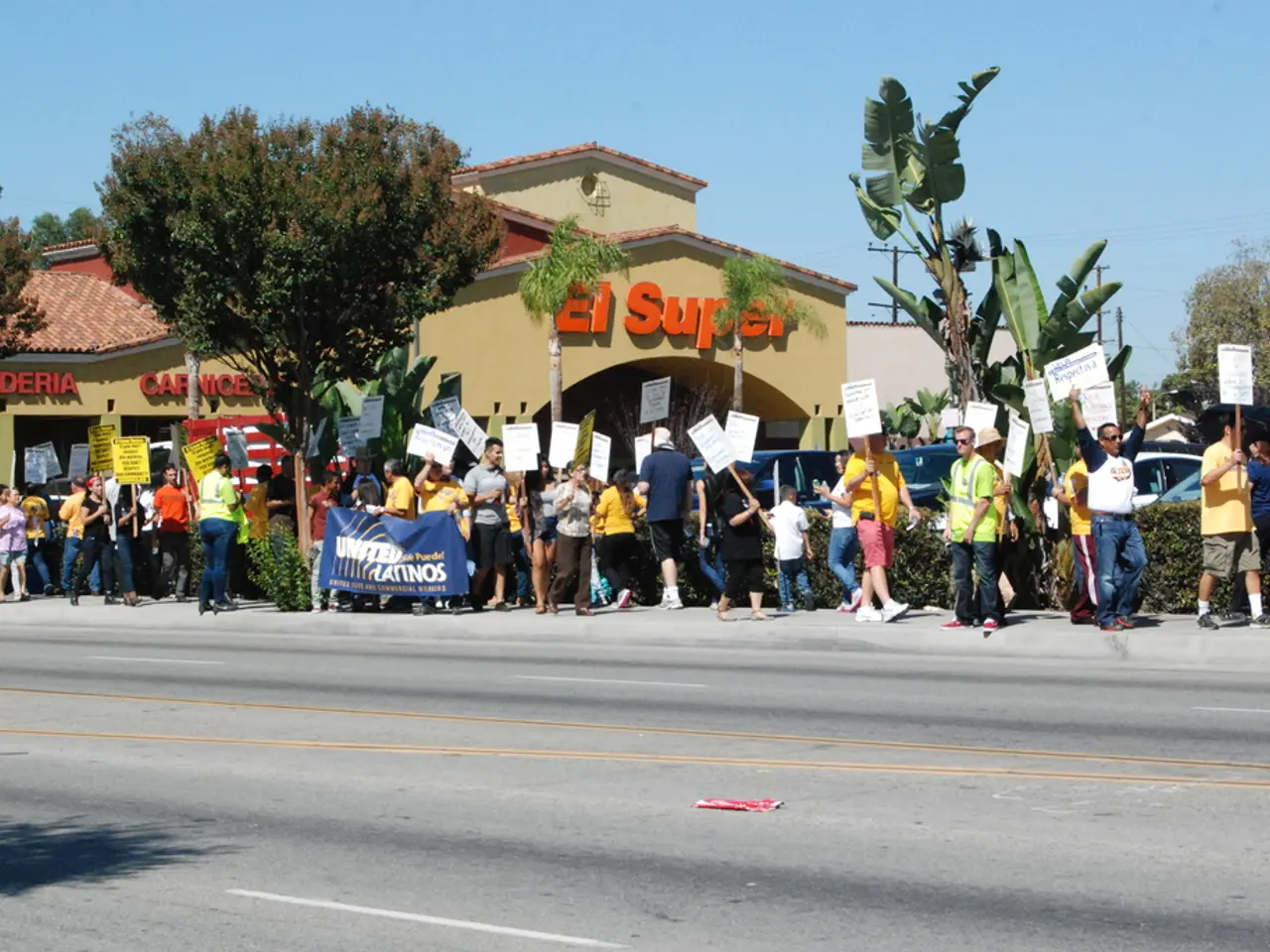 There are group of people holding placards and walking. These are the trees. I can see small...