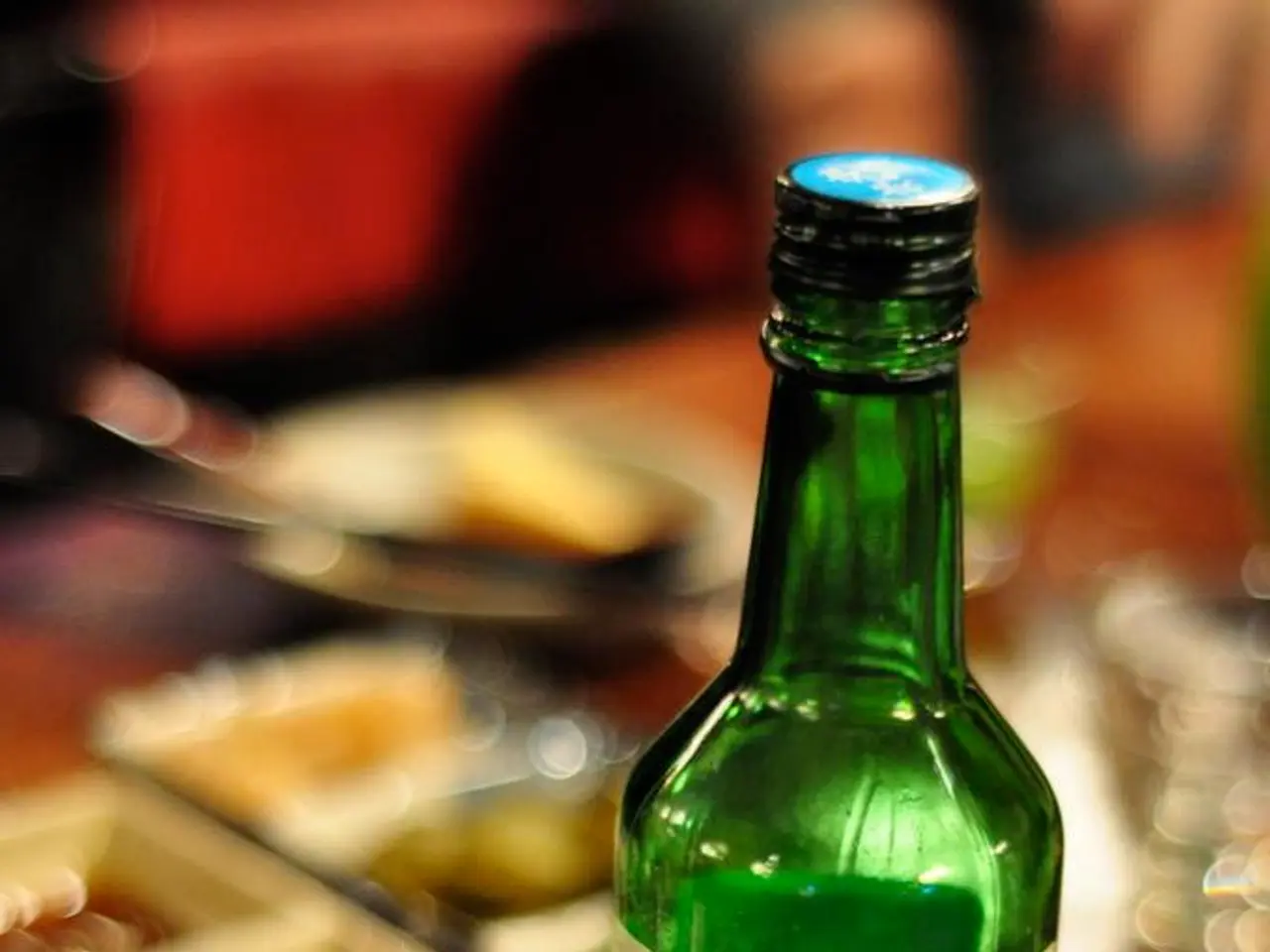 In this image there is a beer bottle with a label and a lie, there is a glass bowl on a table, in...