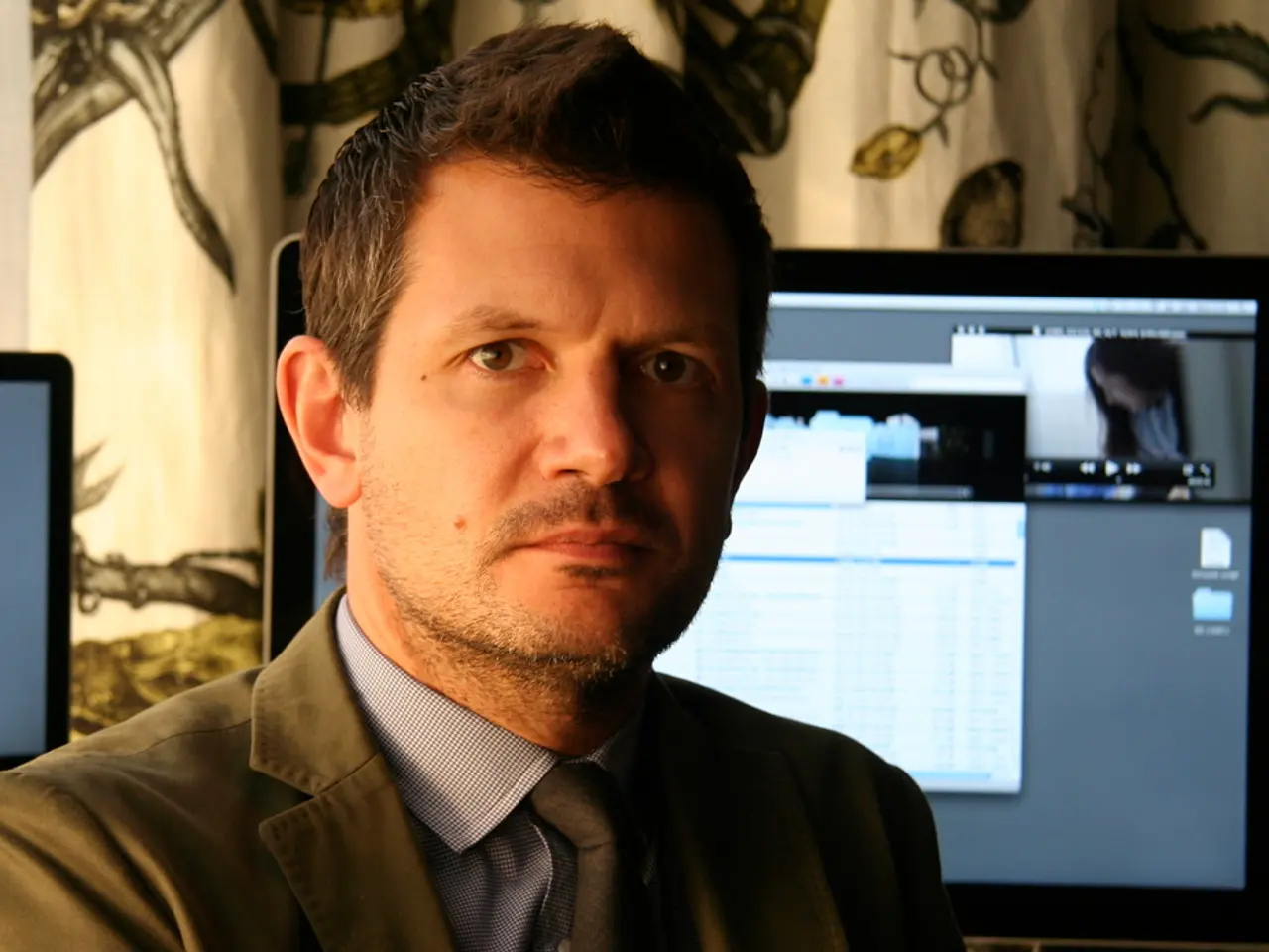 In this image we can see a man, he is wearing the suit, at back here is the computer, where is the...