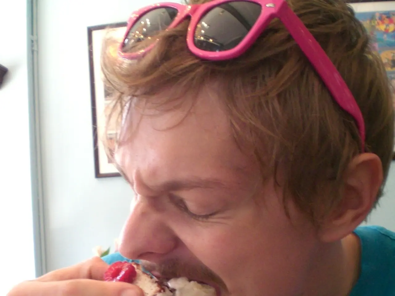 This person is eating a food. Pictures are on the wall.