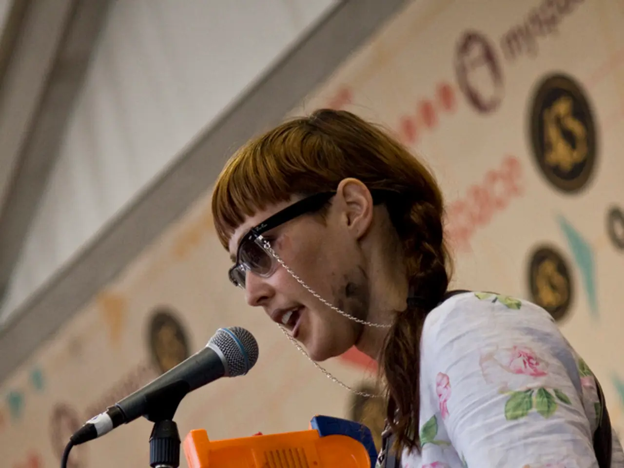 This image consists of a woman wearing white shirt and shades is singing. In front of her, there is...