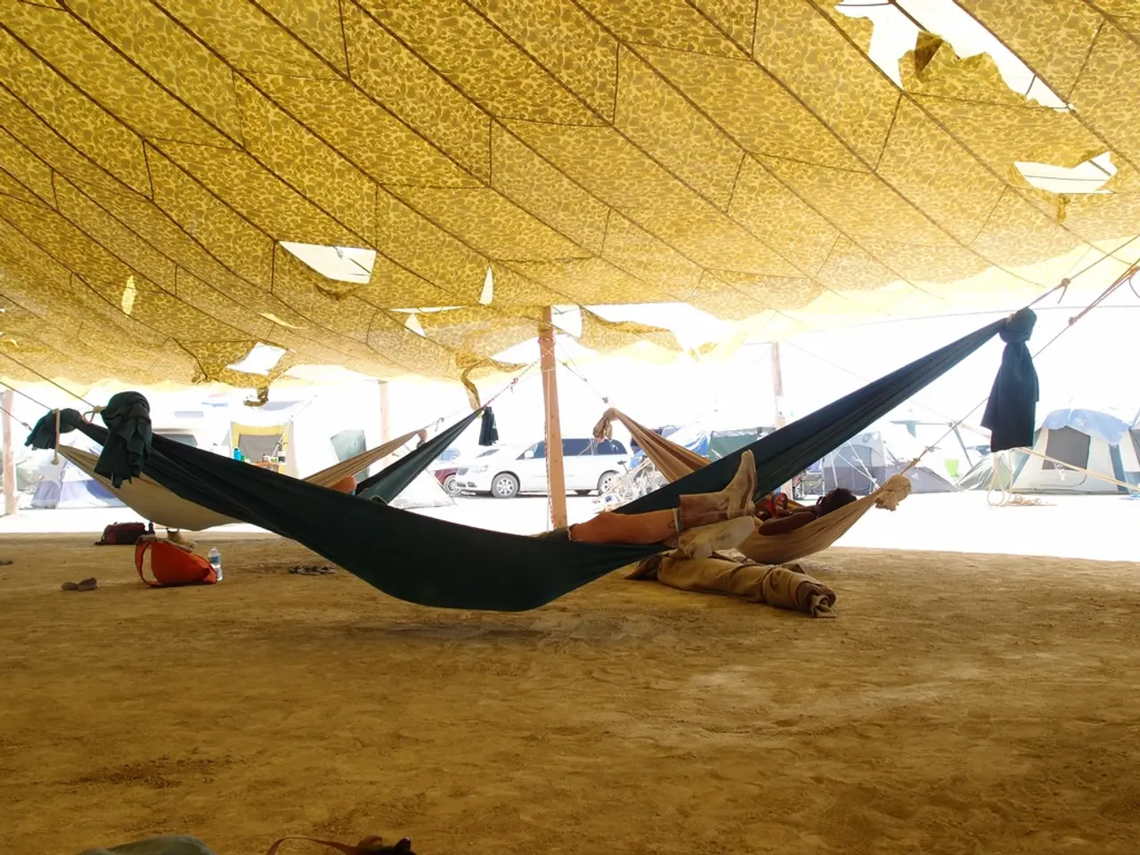 In this image we can see few people sleeping in the swing, there are few tents, a car in the...