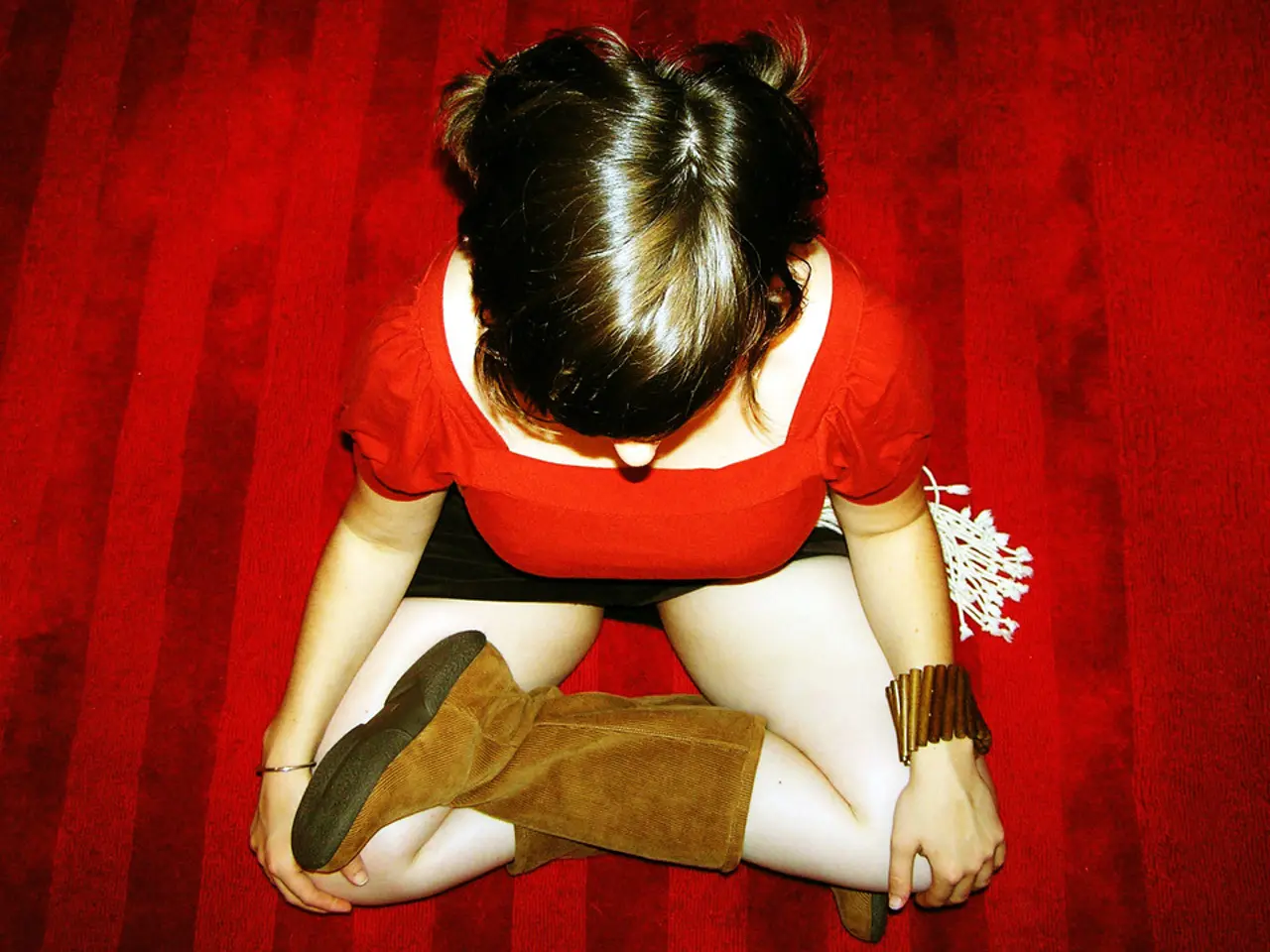 In this image we can see a woman wearing red dress and long boots is sitting on the red color...