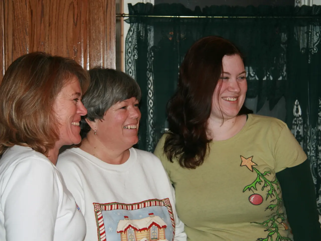 In the foreground of the image there are women standing and laughing. In the background of the...