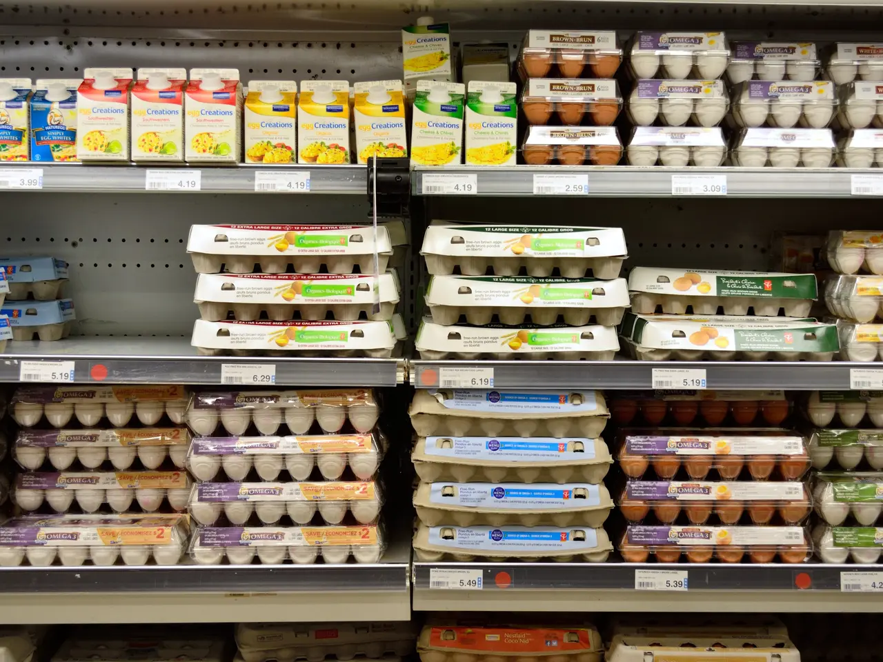 The image shows a grocery store shelf filled with lots of different types of eggs, each with a...