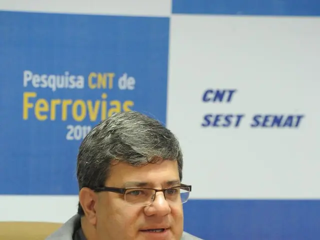 In this image there is a person sitting in a chair is speaking in a mic which is in front of him on...