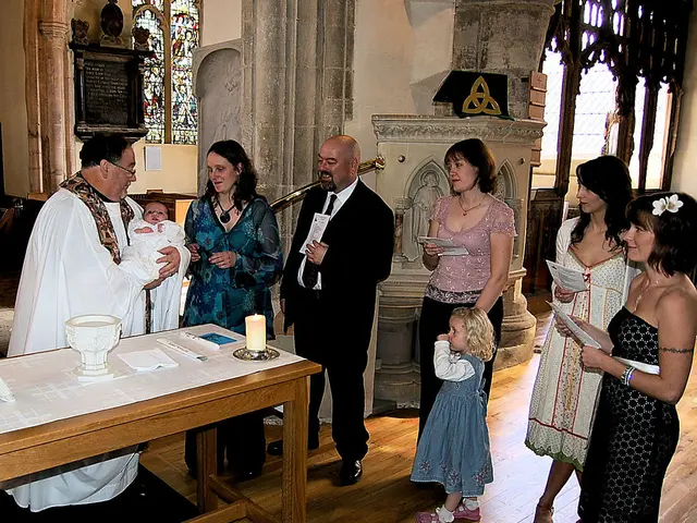 On the left hand side, there is a man in white color dress holding a baby. Beside him, there is a...