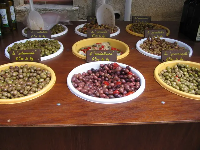 In this image there is a wooden table. On the table there are olives and fruits in the bowls....