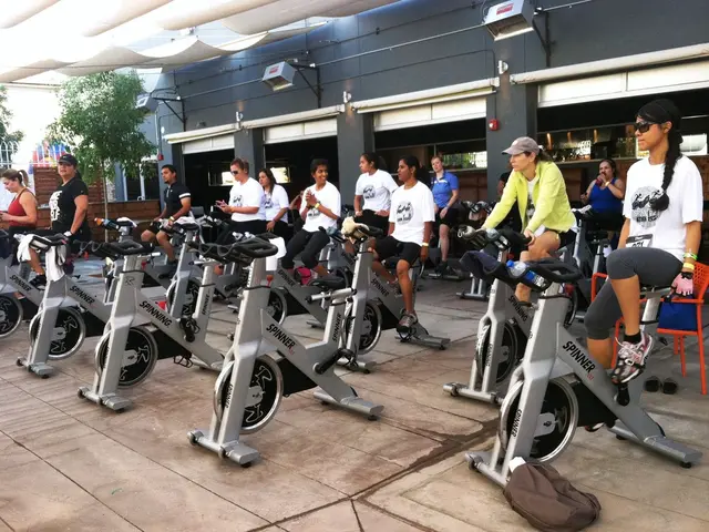 In this image I can see there are exercise cycles. Few people are doing workout on them, they wore...
