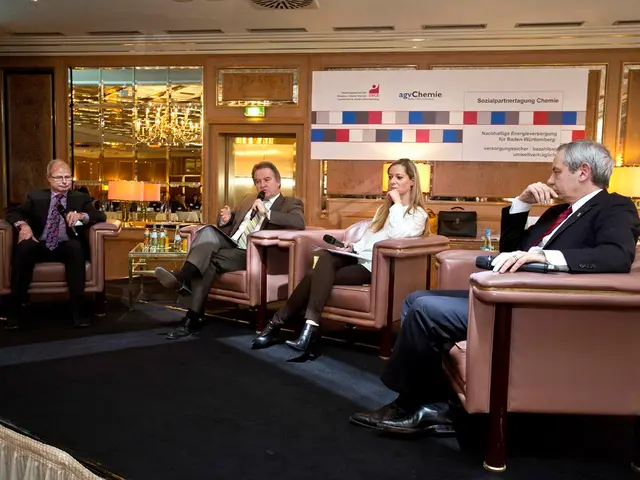 In this image there are four person sitting on the chair. At the back side there is bag and a water...