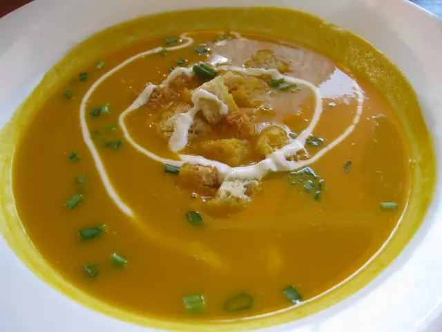 There is a yellow color soup in the white color bowl.