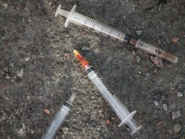 In this image we can see syringes on the ground, there is a needle to one of the syringe.