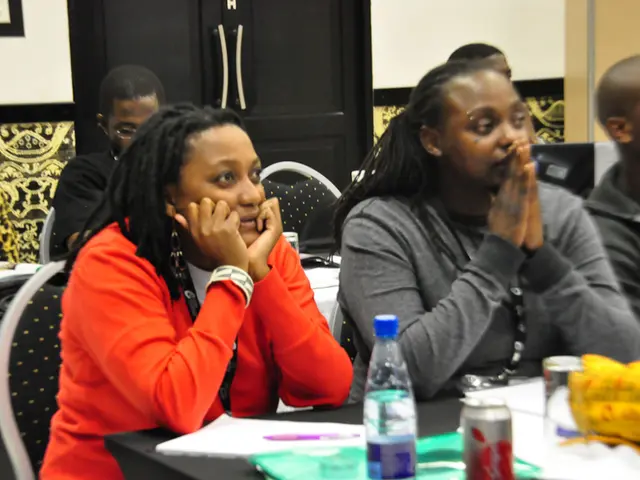 In the image we can see there are people sitting on chair and on table there is a water bottle,...