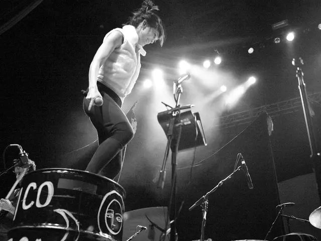 In this image there is a woman holding a mic in her hand is standing with a smile on her face, in...