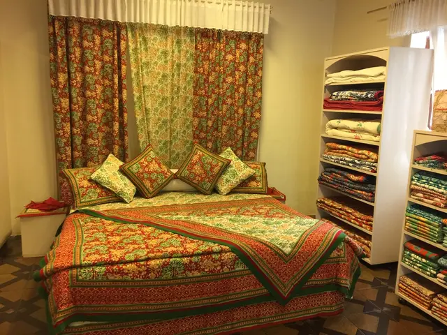 In this image there is a bed, pillows, table, cupboards, walls, curtains, tile floor, window and...