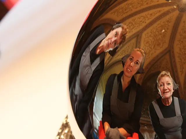 There is a ball on which, there is a mirror image of three women who are smiling and slightly...