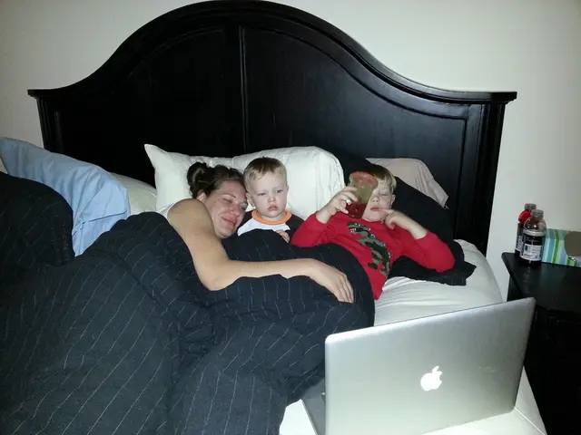 In the image w can see two boys and a women lying on a bed and a system is kept in front of them....