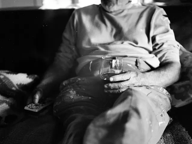 Here in this picture we can see a person sitting on a couch over there and he is holding a remote...