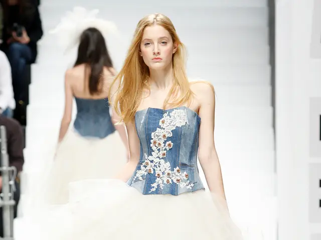 Here in this picture we can see two women walking on the ramp with some designer clothes over a...