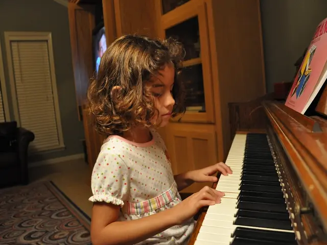 Here we can see a child playing a piano which is present in front of her and there is a book on the...