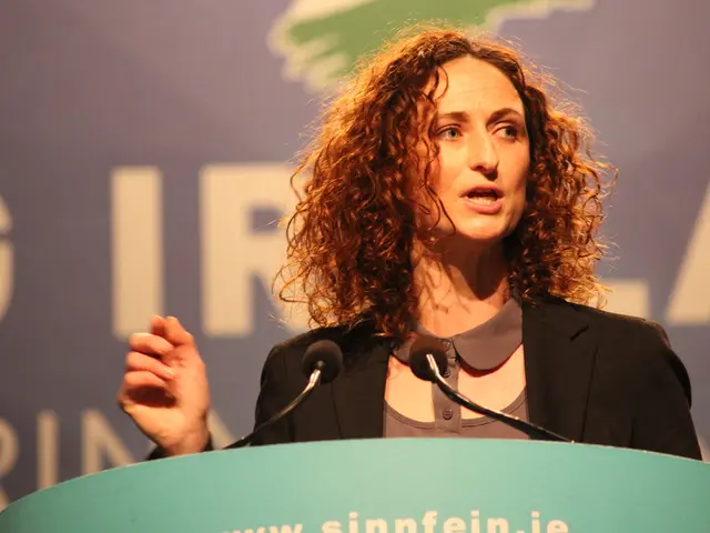 In the picture we can see a woman standing near the microphone and giving a speech and she is...