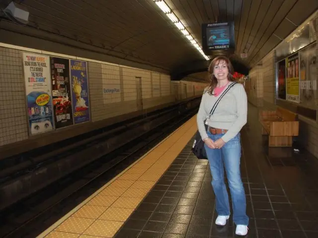 In the image there is a woman standing on the platform of a subway railway station, around the...