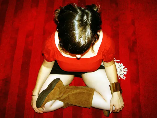 In this image we can see a woman wearing red dress and long boots is sitting on the red color...