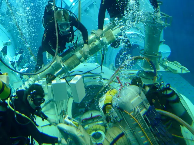 In this image we can see the persons under water and holding an object which looks like a machine....