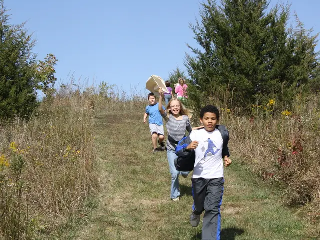 There are three kids running on a greenery ground and there are few other people behind them and...