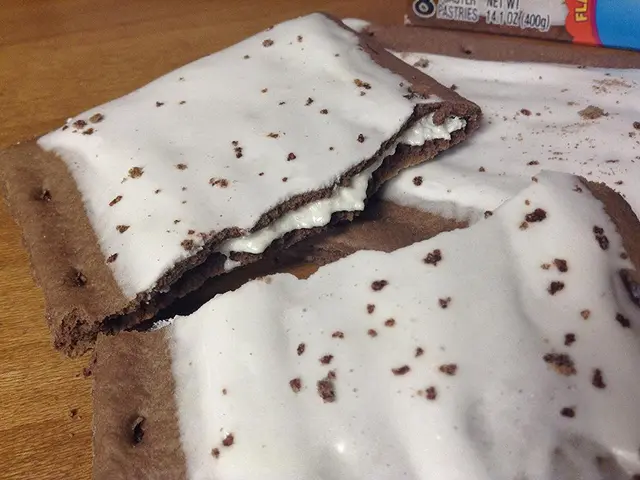 In this image we can see a broken biscuit with cream placed on the table.