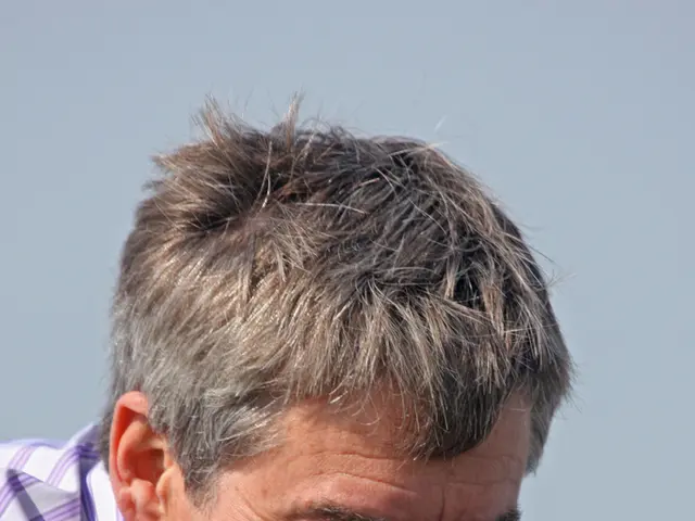 In this picture we can see a man is smiling in the front, there is the sky in the background.