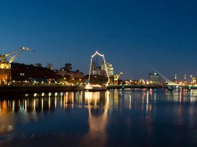 In this image I can see water, background I can see few lights, buildings, and sky is in blue...