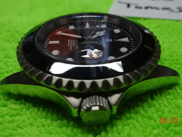 In this image we can see there is a wristwatch on the green color mat and at the back we can see a...