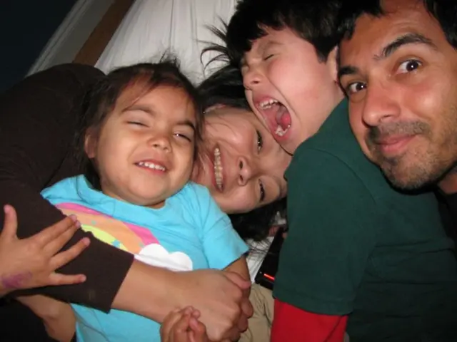 In this image we can see a group of people lying on a bed. We can also see a device on it.