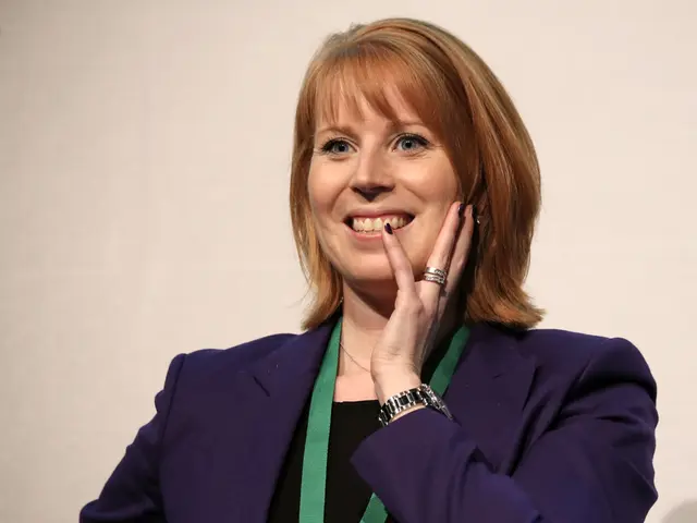 In this image we can see a person wearing blue color suit, green color ID card, also wearing wrist...