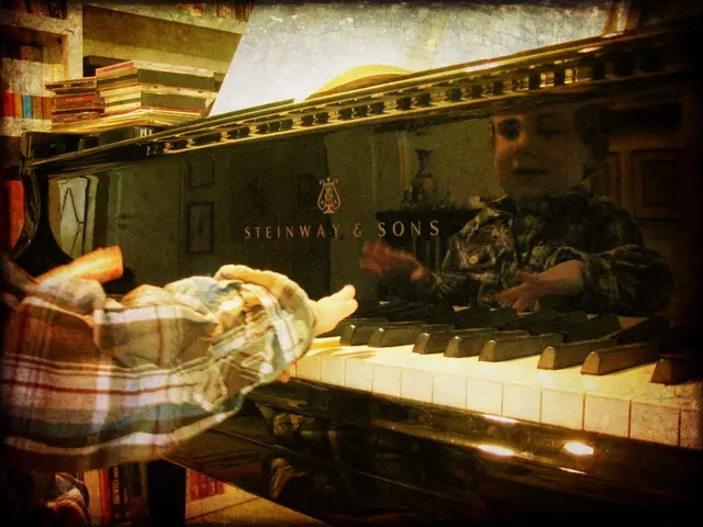 There is a kid playing with a piano in front of him.