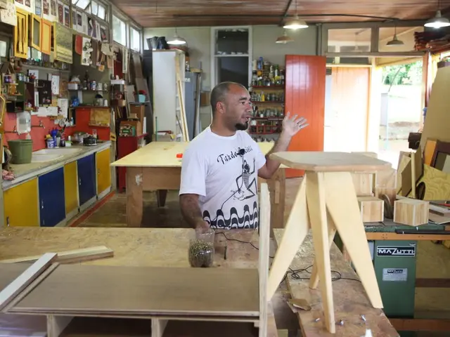 The man in the middle of the picture wearing white T-shirt is standing in front of the table. He is...