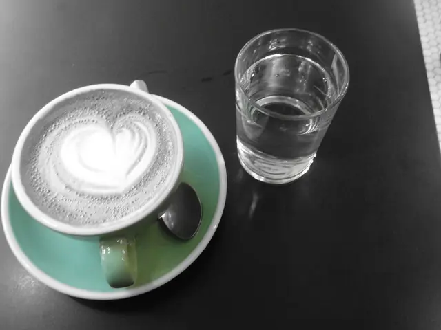 A coffee cup and a glass of water are placed on a table.
