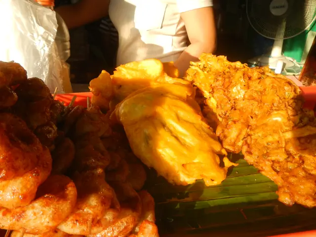 The image shows a plate of food sitting on top of a table, with a person standing in the...