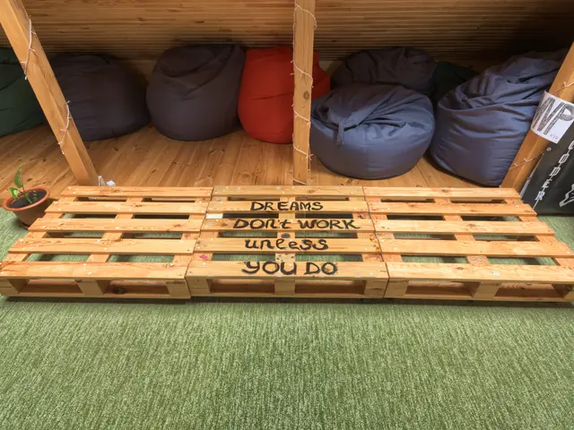 The image shows a wooden pallet with a sign that reads "Dreams Don't Work Unless You Do" on it,...