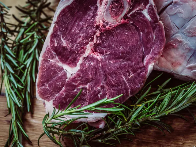 The image shows two raw beef steaks on a wooden cutting board with rosemary sprigs scattered around...