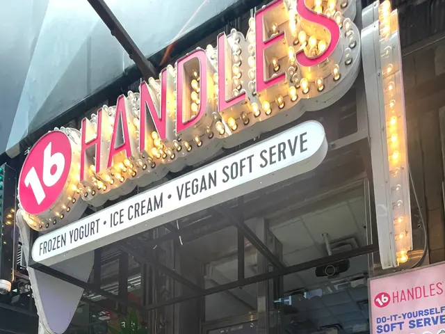 The image shows a store front with a sign that reads "16 Handles Vegan Soft Serve" and a person...