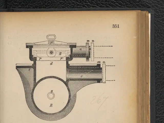 The image shows an open book with a drawing of a machine on it. The drawing is detailed and shows...