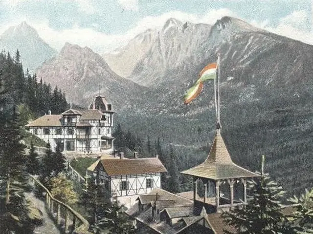 The image shows an old postcard of a building with a flag on top of it, surrounded by trees and a...