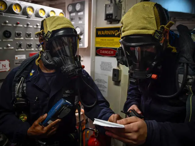 The image shows two men in gas masks standing next to each other in front of a control panel. They...