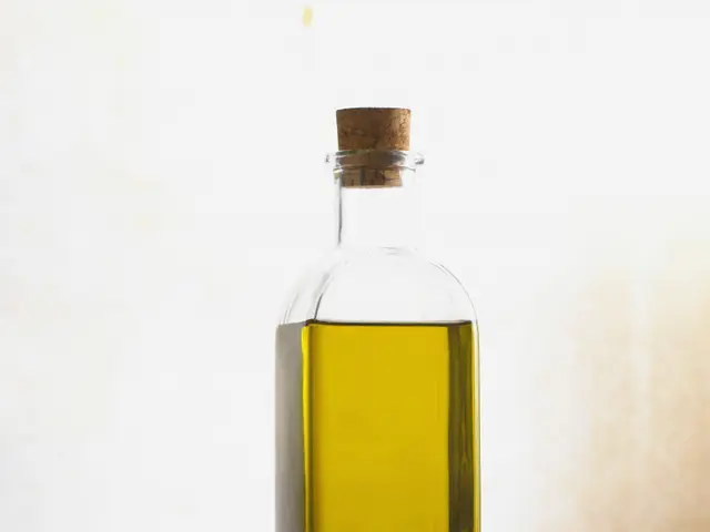 The image shows a bottle of extra virgin olive oil with a cork stopper and a bowl of the same oil...