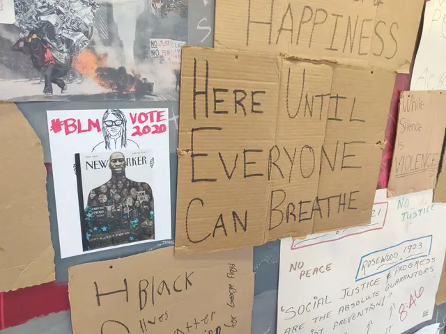 The image shows a wall with a variety of posters and boards attached to it, each with text written...