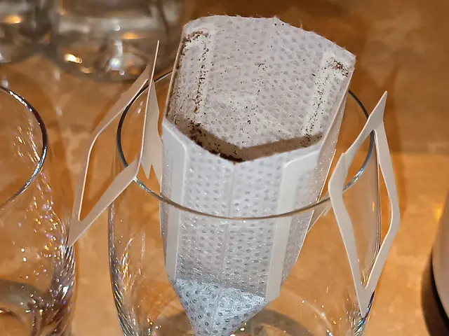 The image shows a glass filled with a cup of tea sitting on top of a table, accompanied by two...