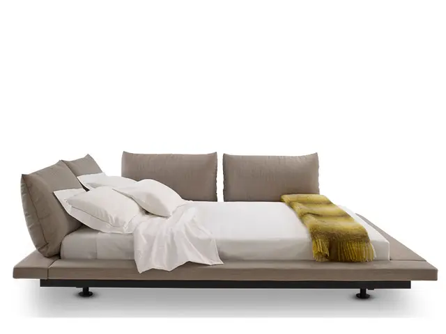 The image shows a bed with pillows and a blanket on top of it, creating a cozy and inviting...