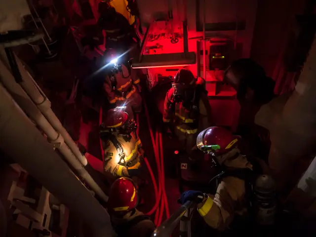 The image shows a group of firefighters wearing helmets and oxygen cylinders, standing in a dark...